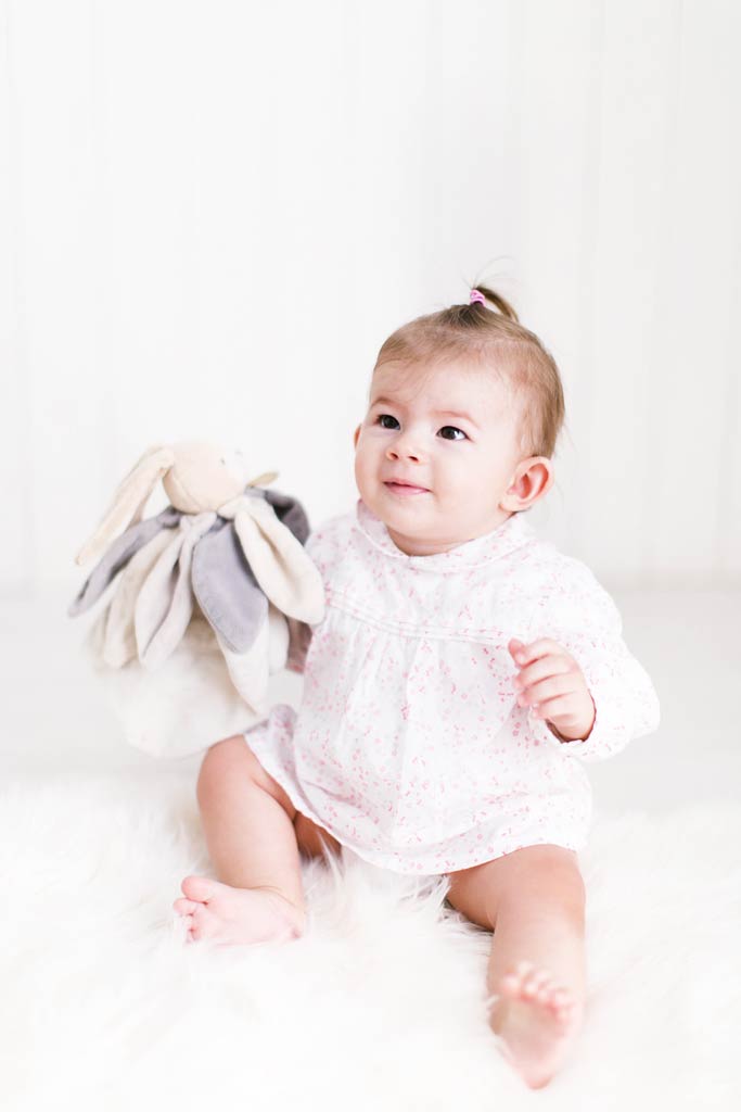 bébé tient assis avec son doudou